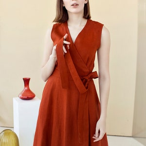 May include: A rust-colored linen wrap dress with a V-neckline and a tie at the waist.