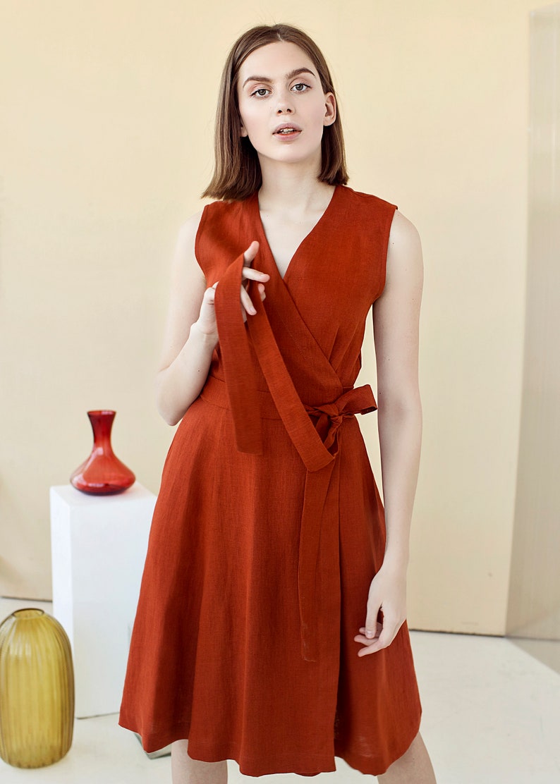 May include: A rust-colored linen wrap dress with a V-neckline and a tie at the waist.