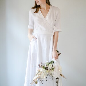 White linen wrap maxi dress with V neck, bride smiling with a dried flower bouquet
