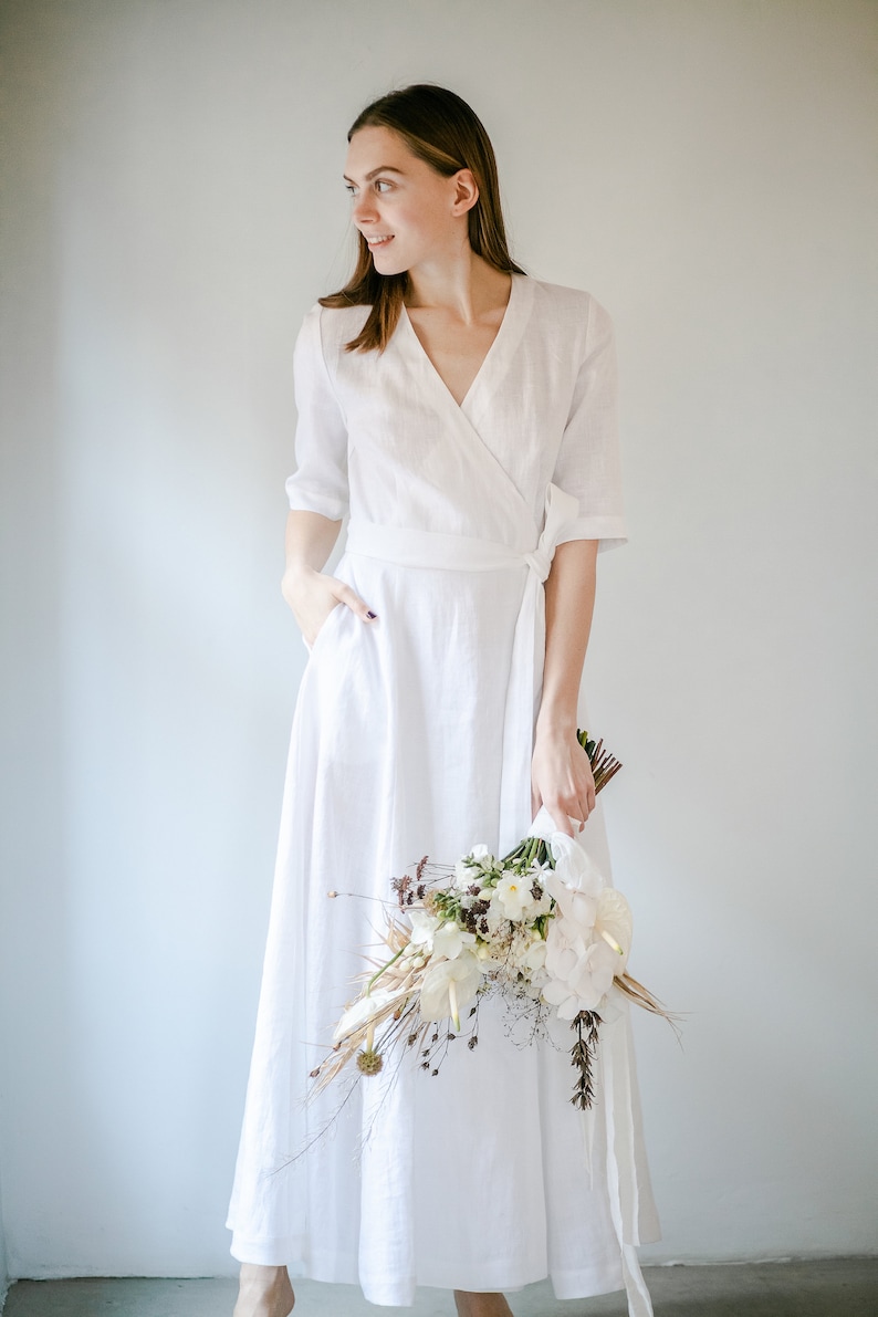 White linen wrap maxi dress with V neck, bride smiling with a dried flower bouquet