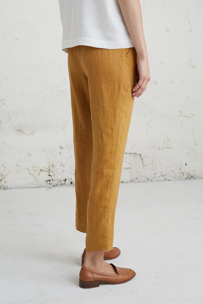 May include: A pair of mustard yellow linen pants with a straight leg fit. The pants are cropped above the ankle and have a simple, classic design.
