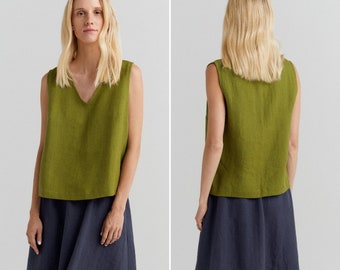 May include: An olive green sleeveless top with a V-neck is worn with a navy blue skirt. The top is made of a textured material, and the skirt has a flowing shape. The outfit is simple and elegant, suitable for casual or semi-formal wear.