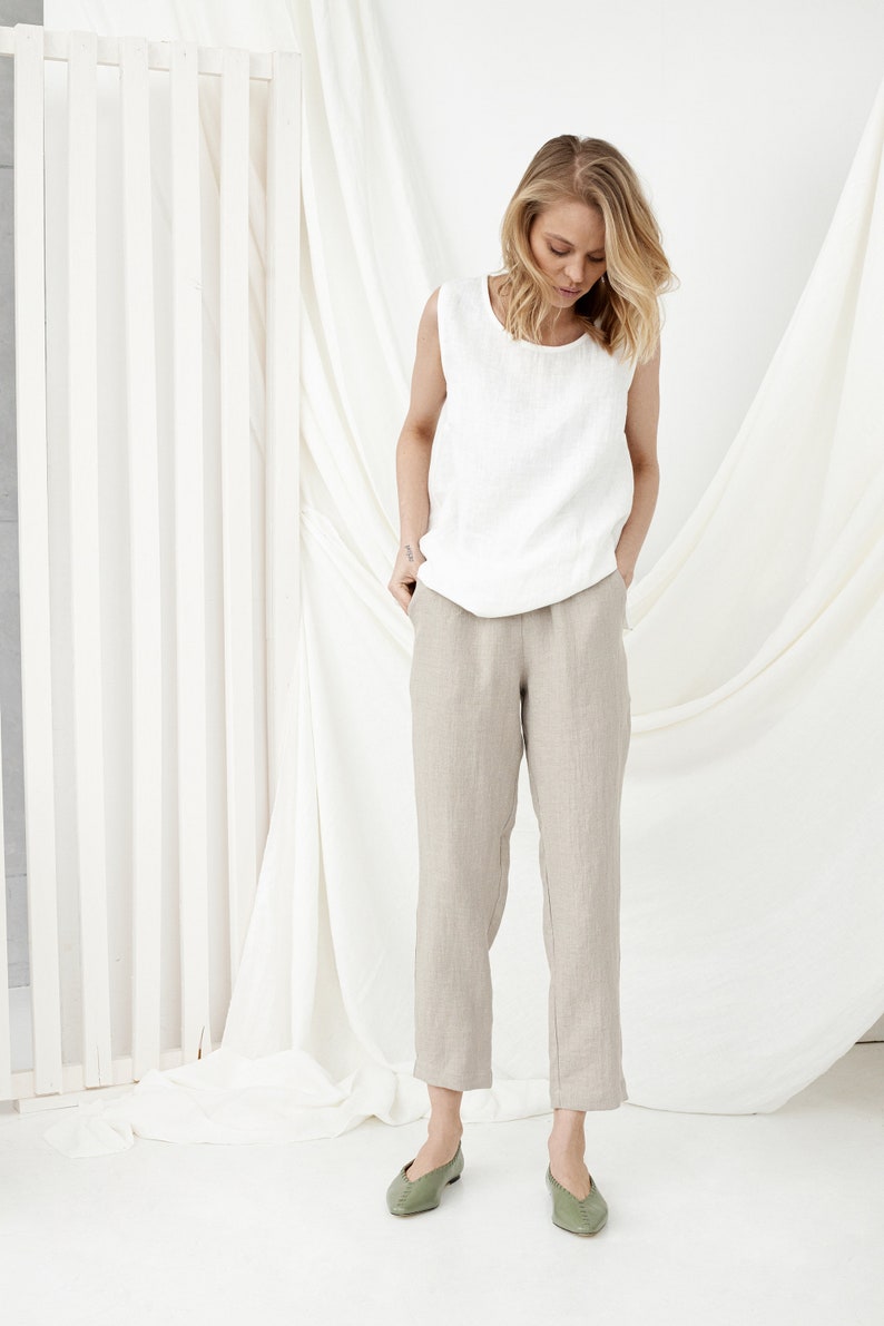 White linen tank top with Natural Linen tapered pants and green flats, model in front of draped white fabric