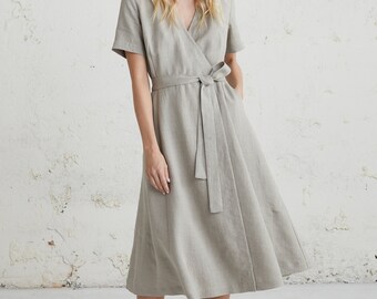 May include: A light gray linen wrap dress with short sleeves and a self-tie belt. The dress has a midi length and a slightly flared skirt.