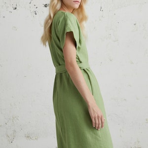May include: A green linen dress with a V-neckline, short sleeves, and a tie belt at the waist.