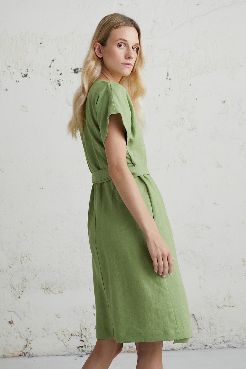 May include: A green linen dress with a V-neckline, short sleeves, and a tie belt at the waist.