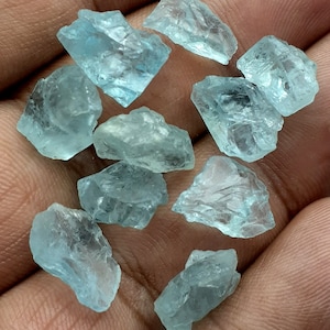 Puede incluir: Una colecci&oacute;n de diez piedras preciosas de aguamarina en bruto. Las piedras son de color azul claro y tienen una variedad de formas y tama&ntilde;os.