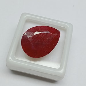 以下が含まれることがあります： 透明なプラスチック製の箱に置かれた、洋梨型の深い赤色の宝石