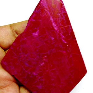 Può includere: Una grande gemma rosa di forma irregolare con un motivo marmoreo. La gemma è liscia e lucidata.