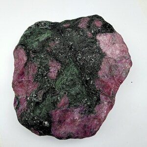 May include: A large, rough, dark green and pink ruby crystal. The crystal has a natural, unpolished surface.