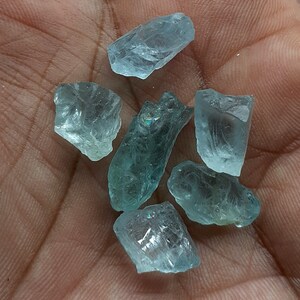 Puede incluir: Seis cristales de aguamarina en bruto de diferentes tama&ntilde;os y formas. Los cristales son transl&uacute;cidos y tienen un ligero tono verde.