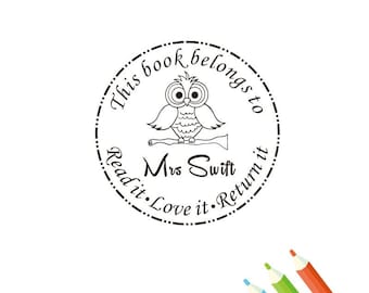 May include: A circular stamp with an owl illustration perched on a branch. The stamp reads "This book belongs to Mrs. Swift. Read it. Love it. Return it." The design is in black ink on a white background. Colored pencils are in the bottom right corner.