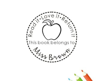 May include: Black and white stamp with a dashed border. The stamp features an apple with a leaf, the text "Read it • Love it • Return it", and the text "This book belongs to Miss Brown".