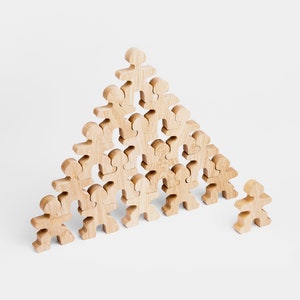 Könnte beinhalten: Eine Holzpyramide aus kleinen Holzfiguren, jede mit einer einfachen menschlichen Form. Die Figuren sind in Pyramidenform angeordnet, wobei die größte Figur oben und die kleinsten Figuren unten sind. Die Figuren sind alle aus der gleichen Holzart gefertigt und haben eine natürliche Oberfläche.