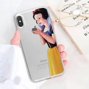 Puede incluir: Funda transparente para iPhone con un diseño de Blancanieves sosteniendo una manzana. El vestido es amarillo, la parte superior azul y el lazo rojo. La funda es transparente y deja ver los detalles del teléfono. La palabra "iPhone" está impresa.