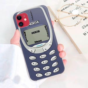 May include: A blue and silver phone case with a Nokia logo and a screen that says "NOKIA" and "Menu". The case has a keypad with numbers and letters.