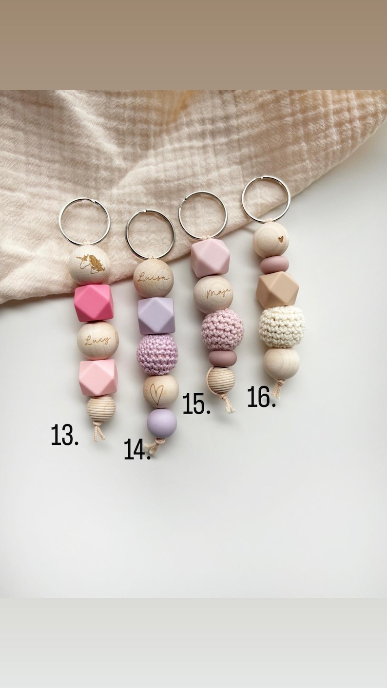 May include: Four keychains with wooden and silicone beads in various shapes and colors. Each keychain has a silver ring and is personalized with a name. One keychain features a unicorn design. Numbers 13, 14, 15, and 16 are visible.
