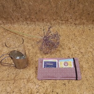 Könnte beinhalten: Ein rosa-weißer Stoffbeutel für Teebeutel mit zwei Teebeuteln darin. Die Teebeutel sind mit "Melmer Earl Grey" und "Tea Forte" beschriftet.