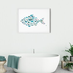 K&ouml;nnte beinhalten: Ein gerahmter Kunstdruck mit einem Fisch, der aus verschiedenen blauen und t&uuml;rkisfarbenen Fischformen besteht. Das Kunstwerk h&auml;ngt an einer wei&szlig;en Wand &uuml;ber einer wei&szlig;en ovalen Badewanne. Das Badezimmer hat ein modernes, minimalistisches Design.