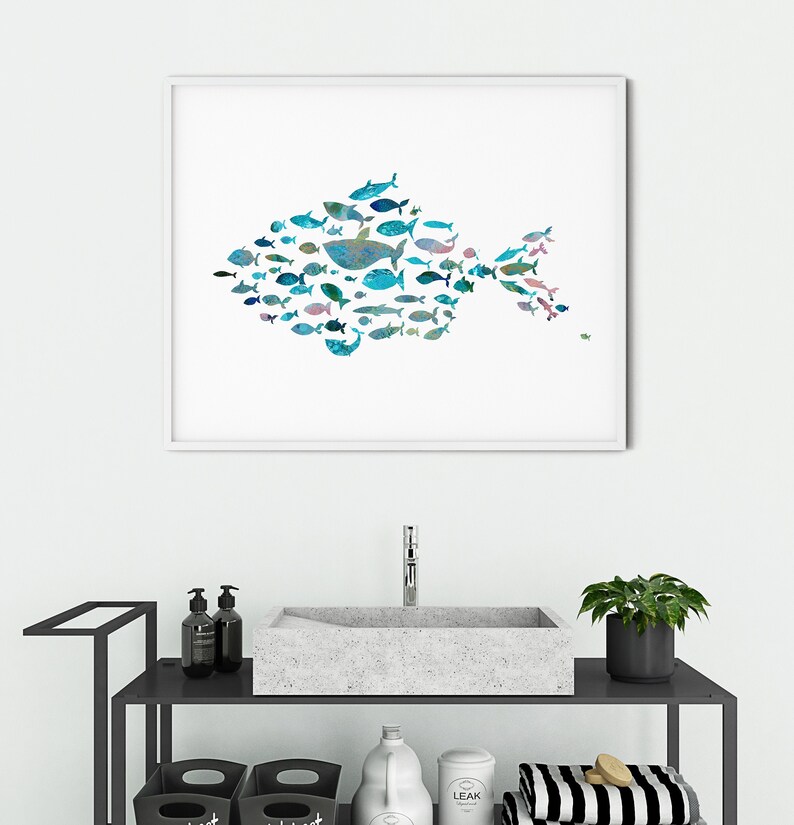 K&ouml;nnte beinhalten: Ein gerahmter Kunstdruck mit einem gro&szlig;en Fisch, der aus zahlreichen kleineren Fischen in Blau-, T&uuml;rkis- und Gr&uuml;nt&ouml;nen besteht. Das Kunstwerk wird &uuml;ber einem Waschbecken im Badezimmer ausgestellt und verleiht dem Raum ein maritimes Thema. Der Druck ist in einem wei&szlig;en Rahmen.