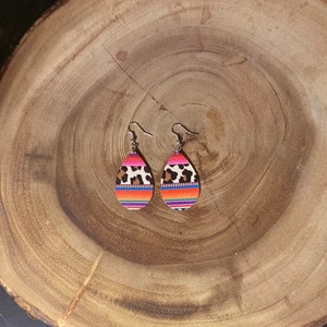 May include: A pair of teardrop-shaped earrings with a pink, orange, and blue striped pattern and a leopard print design.