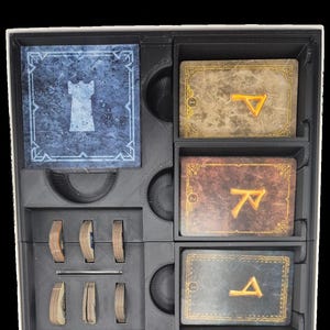 Peut inclure: Un insert d'organisation de jeu en plastique noir pour le jeu de cartes Le Seigneur des Anneaux : La Communauté de l'Anneau Duel pour l'extension La Terre du Milieu. L'insert comporte des compartiments pour les cartes, les jetons et les autres composants du jeu. L'insert est étiqueté "Le Seigneur des Anneaux Duel Insert Pour La Terre Du Milieu".