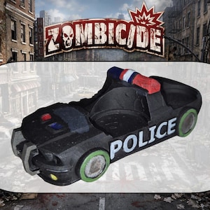 Puede incluir: Un modelo de coche de policía negro con la palabra POLICE en letras blancas en el lateral, ruedas con borde verde y una barra de luces roja, blanca y azul en el techo. El vehículo tiene un interior hueco y está sobre un fondo de juego Zombicide.