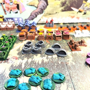 May include: A game board with various colorful game pieces, including small houses, trees, and tokens. The board is made of wood and has a brown background. The game pieces are made of plastic and are in various colors, including green, blue, red, and yellow.