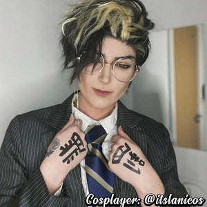 May include: A person wearing a black and white striped suit jacket with a white collared shirt and a blue and yellow striped tie. The person has black and blonde hair and is wearing round glasses. The person has black ink markings on both hands. The text "Cosplayer: @itslanicos etsy.com/shop/AlunaCreates" is visible at the bottom of the image.