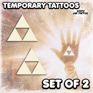 Puede incluir: Juego de 2 tatuajes temporales con un diseño de triángulo color crema y un recorte de triángulo más pequeño. La imagen incluye el texto "TEMPORARY TATTOOS" y "WHITE INK TATTOO". También se muestran las palabras "SET OF 2".
