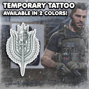 Puede incluir: Tatuaje temporal disponible en 2 colores. El diseño presenta un yelmo de caballero, una espada y una corona de laurel. El tatuaje es en tonos grises y blancos. El fondo es una imagen borrosa de una persona con equipo militar.