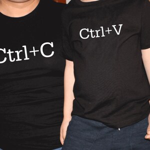 May include: Two black t-shirts with white text. The shirt on the left says "Ctrl+C" and the shirt on the right says "Ctrl+V".