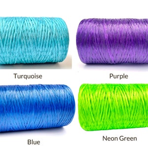 May include: Four spools of colorful raffia ribbon in turquoise, purple, blue, and neon green. Each spool is labeled with its color name. The raffia is tightly wound, showing a textured surface. Ideal for crafting and gift wrapping.