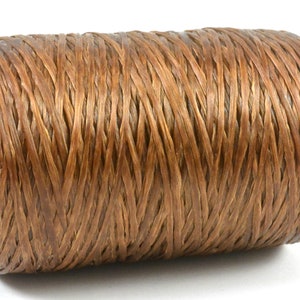 May include: A spool of brown waxed thread, tightly wound and ready for use. The thread is a warm, earthy brown color, and the spool has a cardboard core. Ideal for leatherwork, bookbinding, or other crafts.