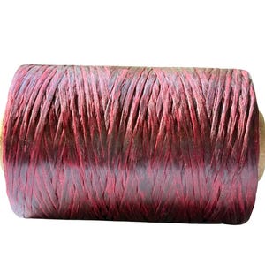May include: A spool of burgundy-colored raffia ribbon. The ribbon is tightly wound and has a textured appearance. The spool's ends are a light brown color. This raffia ribbon is suitable for crafting and gift wrapping.