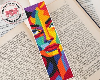 May include: A colorful abstract portrait of a woman's face with a geometric design. The colors are red, orange, yellow, green, blue, and purple. The image is a cross stitch pattern.
