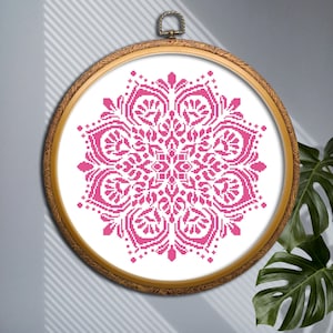 May include: A pink mandala cross-stitch pattern in a wooden embroidery hoop.