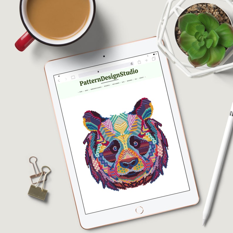 Pu&ograve; includere: Un design di orso panda geometrico colorato sullo schermo di un tablet. Il tablet &egrave; aperto sul sito web PatternDesignStudio.com.