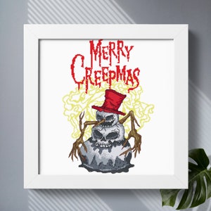 May include: A white framed cross-stitch pattern featuring a snowman with a skull head and a red top hat. The snowman is surrounded by a yellow and white smoke-like design. The text "Merry Creepmas" is written in red above the snowman.