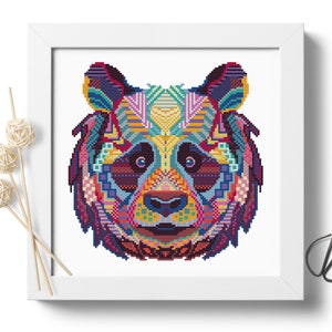 Pu&ograve; includere: Un design di orso panda geometrico e colorato su sfondo bianco. La pelliccia del panda &egrave; composta da varie forme e colori, tra cui blu, viola, rosa, giallo e verde.