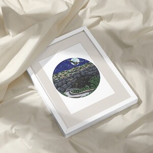 May include: A framed print of a circular illustration depicting a winding road leading into a cave under a full moon with a bat flying overhead. The sky is dark blue with white stars and the cave is made of gray stone.