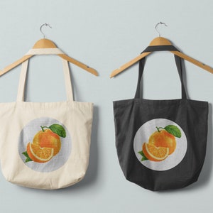 May include: Two tote bags with orange fruit designs. The bag on the left is white with a circle design featuring a whole orange and a slice of orange. The bag on the right is black with a circle design featuring a whole orange and a slice of orange.