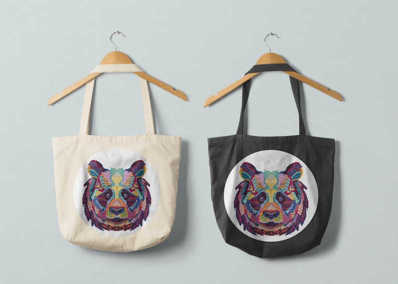 Pu&ograve; includere: Due borse tote con un design di panda geometrico colorato stampato sul davanti. La borsa a sinistra &egrave; bianca e la borsa a destra &egrave; nera.