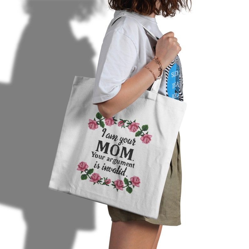 May include: White canvas tote bag with a pink floral border and the text "I am your MOM. Your argument is invalid." printed in black.