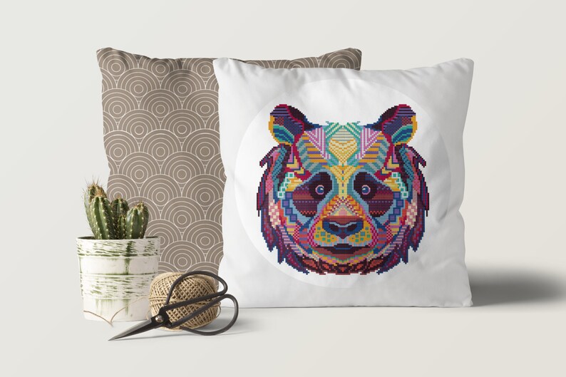 Pu&ograve; includere: Un cuscino bianco con un design di panda geometrico colorato. Il panda &egrave; circondato da un cerchio bianco sul cuscino.