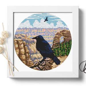 May include: A black raven perched on a branch overlooking a scenic canyon landscape with a natural arch in the distance. The sky is blue with white clouds and a smaller bird flies overhead.