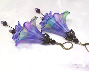 May include: A pair of dangle earrings featuring translucent purple and blue trumpet-shaped flower beads. Each flower is accented with a bronze-toned metal cap, dark purple crystal beads on a thin wire, and a bronze-toned leverback closure.