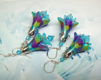 May include: Four pairs of flower-shaped earrings. Each earring features a colorful, translucent floral design in shades of blue, purple, and green, with silver-colored metal accents and a small blue bead. The earrings have a hook and lever back closure.