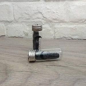 May include: Two small glass jars containing black dental floss. The jars have silver lids and the word "Deeper" printed on the side.