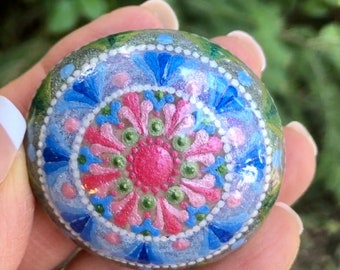 Mandala painted natural rock in pink, blue green and white metallic paint.